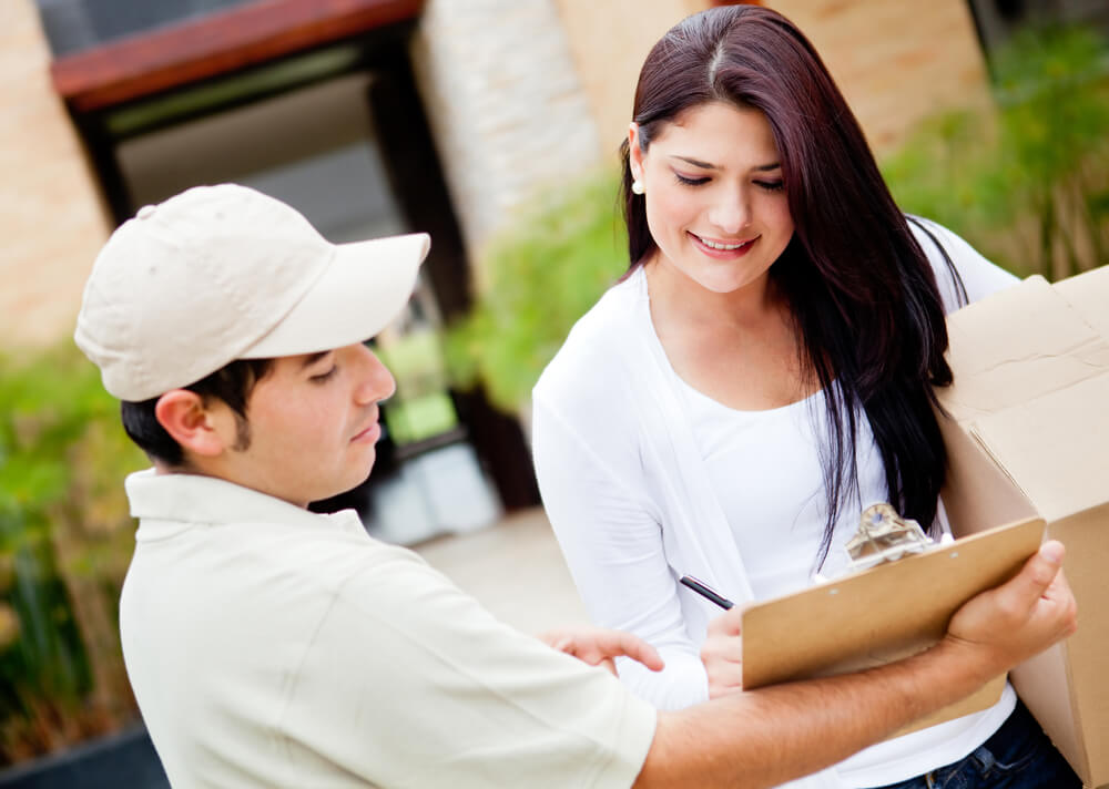 Woman receiving a package at home from a delivery guy